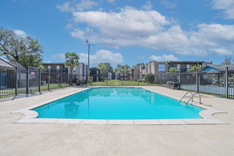 A large outdoor swimming pool surrounded by a fence at The Drake in Bossier City, LA